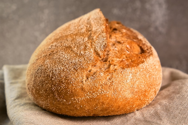 Wholegrain rye bread on a cutting board on grey surface