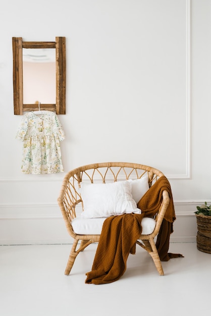 A wicker armchair with a brown plaid in a white room in Scandinavian style