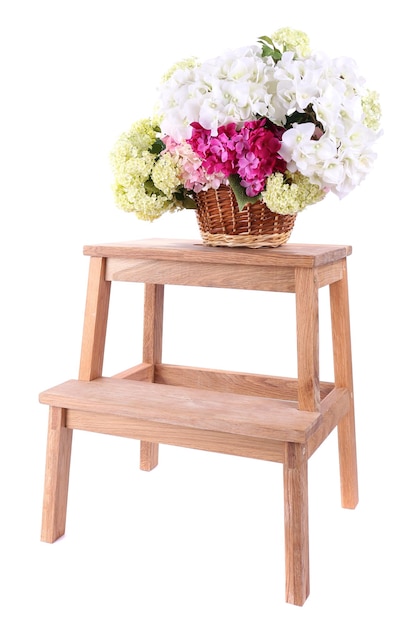 Wicker basket with flowers on small wooden ladder isolated on white