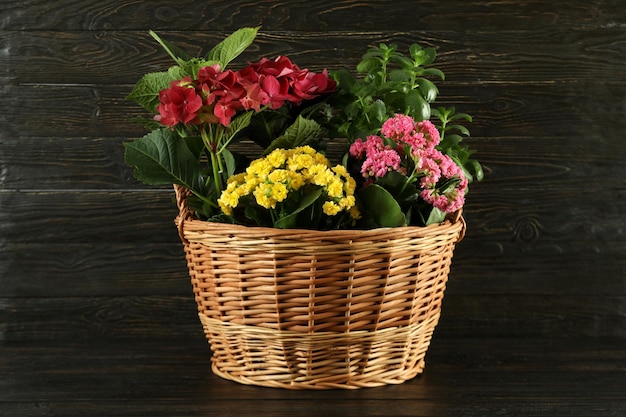 Wicker basket with flowers on wooden table