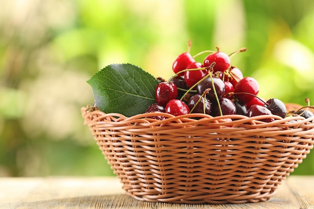 Wicker basket with fresh cherry on table outdoors