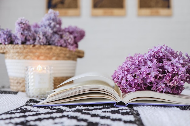 Wicker basket with lilacs a candle an open book on the tableGood morning concept