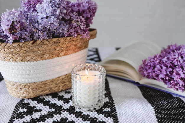 Wicker basket with lilacs a candle an open book on the tableGood morning concept