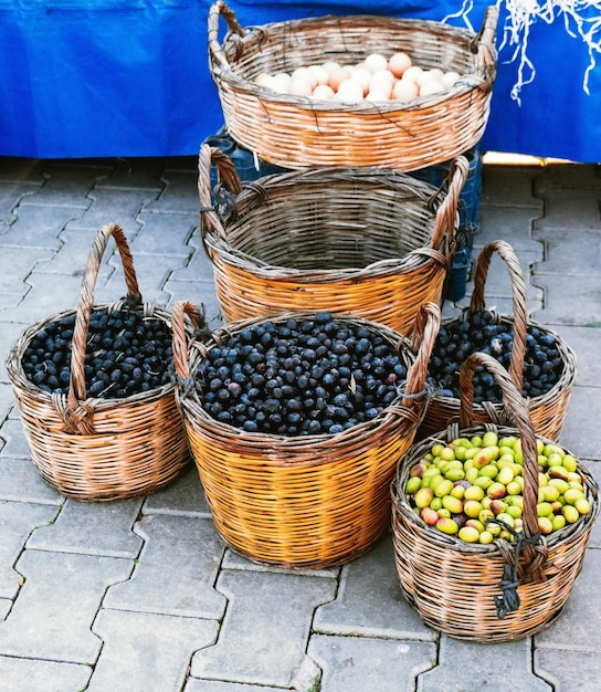 Wicker baskets full of green and black olives standing outdoor on paving stones Street food market in Turkey