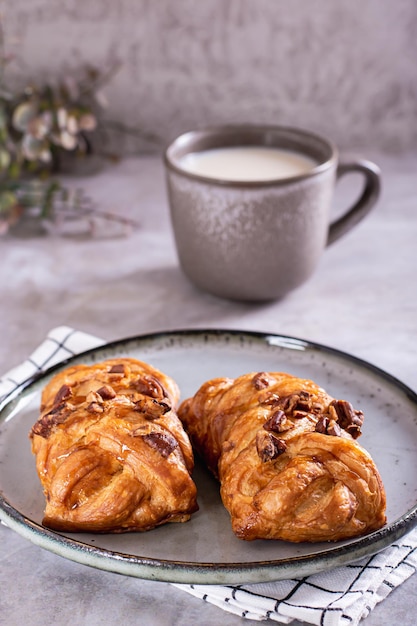 Wicker buns with cinnamon nuts and maple syrup and a cup of coffee for Swedish fika time vertical