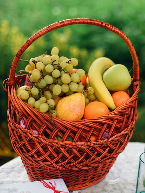 Wicker fruit basket with apples, grapes, bananas and pears