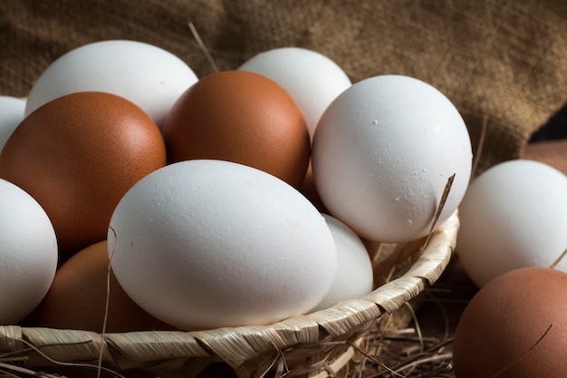 Wicker wooden plate with brown and white eggs on a background of burlap.