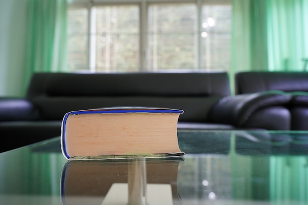 wide angle close up of book on top glass table with blur room background