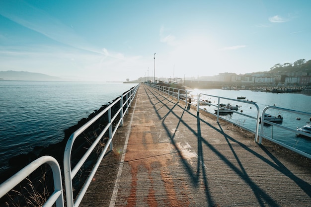 Wide angle shot of pier and port next to the sea and the bicycle lane of town during cloudy day with sun beans