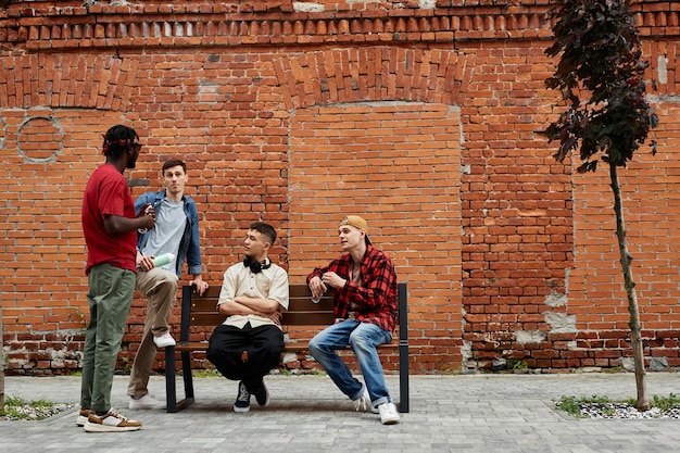 Wide angle view at diverse group of young guys wearing street style fashion in urban city area again