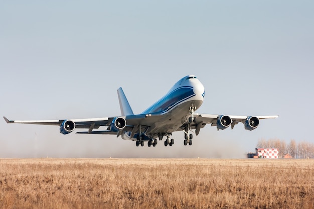 Wide body cargo airplane takes off leaving behind a cloud of dust