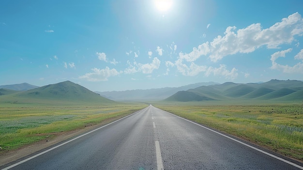 A wide road with grasslands and distant mountains on both side