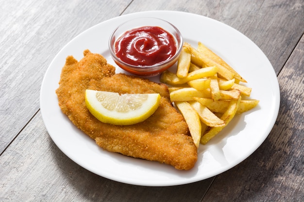 Wiener schnitzel with fried potatoes on wood