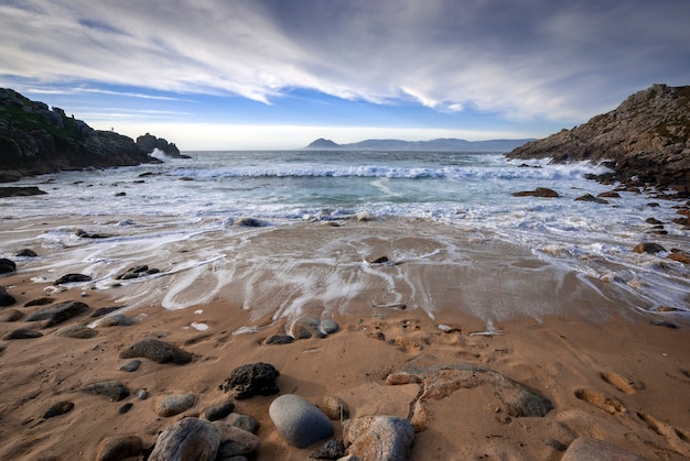 wild beach with sand rocks and clouds