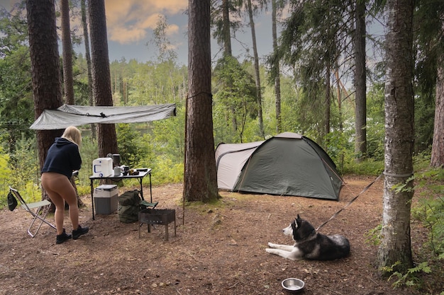 Wild camping in Estonia in nature in the forest near the lake A girl is preparing food