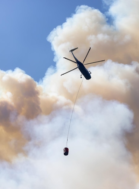 Wildfire Service Helicopter flying over BC Forest Fire and Smoke on the mountain near Hope