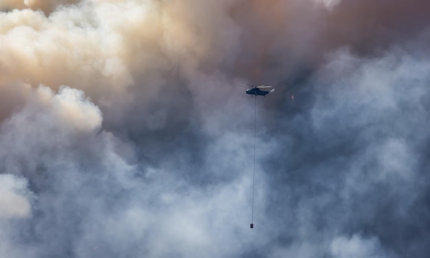 Wildfire Service Helicopter flying over BC Forest Fire and Smoke on the mountain near Hope