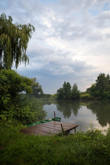 Wildlife pier with a boat with oars The sky after the rain freshness in the air The concept of camping and country rest with tents