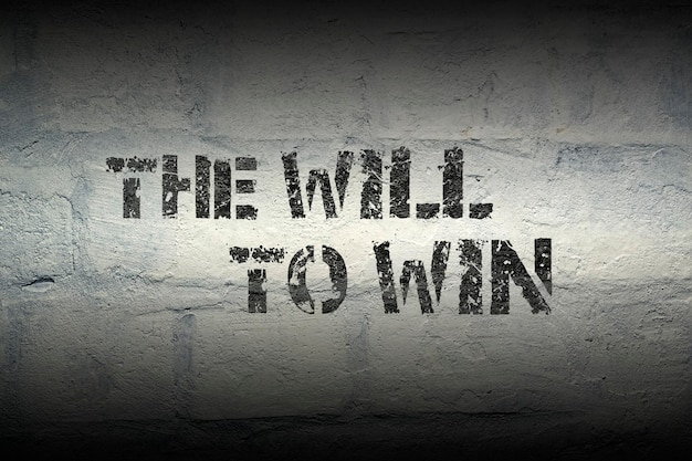 will to win phrase stencil print on the grunge white brick wal