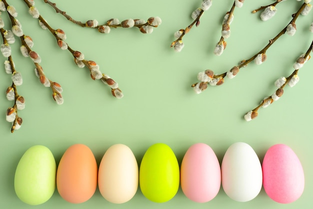 Willow branches and easter eggs on a green background beautiful fluffy sprigs of willow blooming