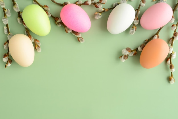 Willow branches and easter eggs on a green background fluffy sprigs of willow blooming colored eggs