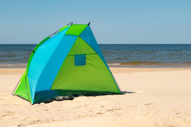 Wind breaker tent on a sandy beach by the sea.