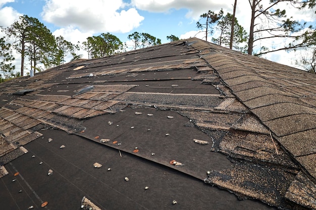 Wind damaged house roof with missing asphalt shingles after hurricane Ian in Florida Repair of home rooftop concept