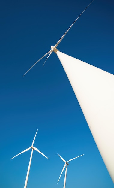 Wind farm with tree power generators against clear blue sky Vertical shot dramatic view from belowxA