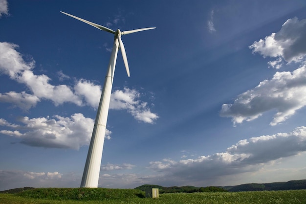 A wind turbine in a field with a blue sky behind it