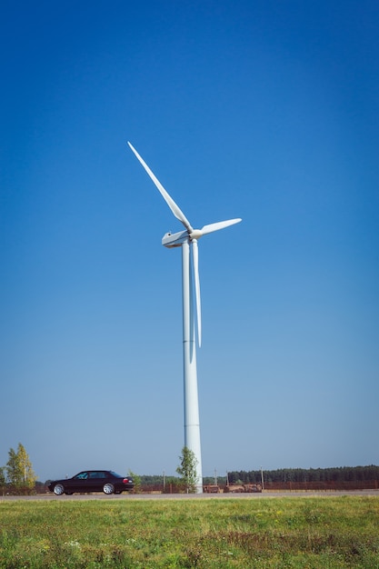 Wind turbine generating electricity on the green field at summer day