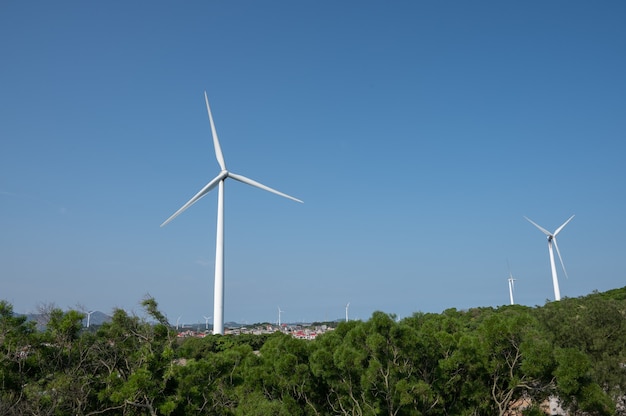 The wind turbine in operation on the mountain is under the blue sky