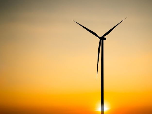 A wind turbine with the sun setting behind it