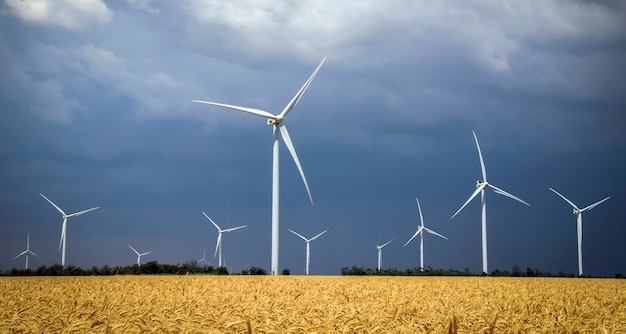 Wind turbines and agricultural field on a summer cloudy day. Energy production, clean and renewable energy.