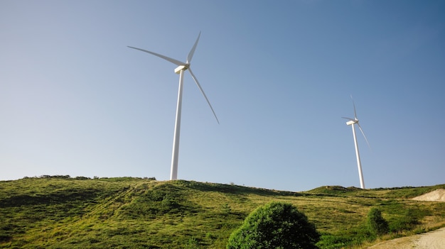 Wind turbines on hills generating electricity over a blue sky background. Clean and ecological energy production concept.