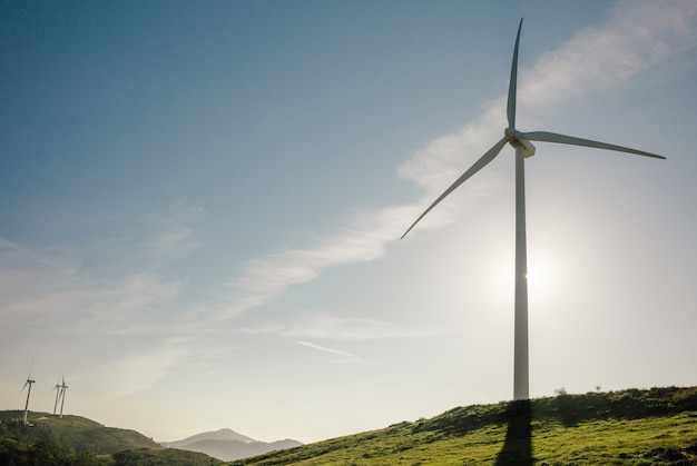 Wind turbines on hills generating electricity over a blue sky. Clean and ecological energy production concept.