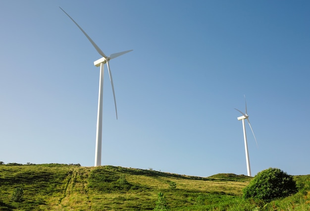 Wind turbines on hills generating electricity over a blue sky. Clean and ecological energy production concept.