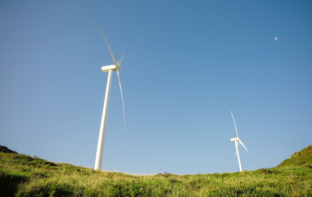 Wind turbines on hills generating electricity over a blue sky. Clean and ecological energy production concept.