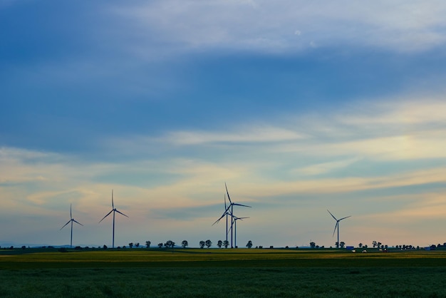 Windmill turbine generator against beautiful sunset sky in countryside area concept of clean renewab