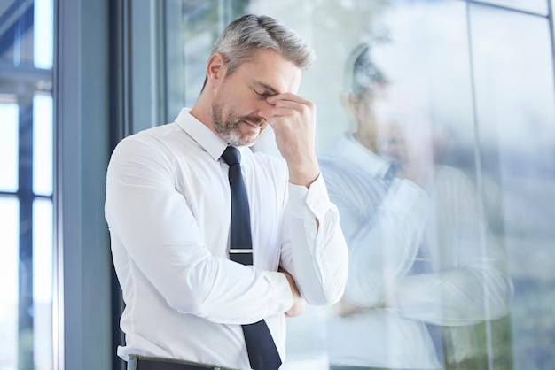 Window business man and stress with headache burnout and overworked in office Senior male entrepreneur and ceo frustrated mental health and leader with depression pain and tired in workplace