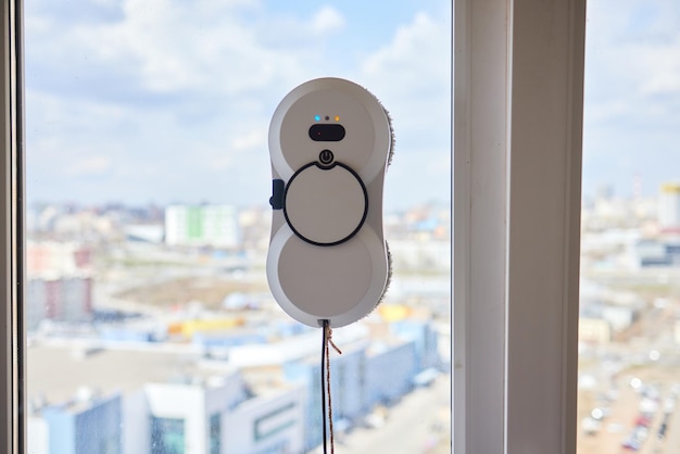 A window cleaner robot washes glass against the backdrop of multistorey buildings