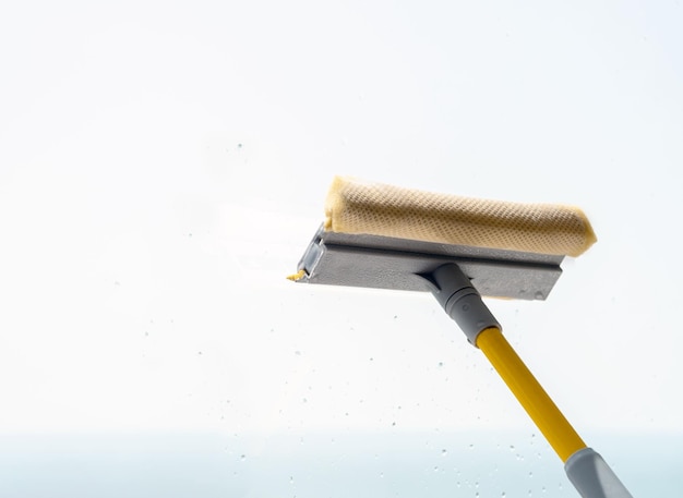 Window cleaning brush scraper on background of dirty wet glass Window washing service concept