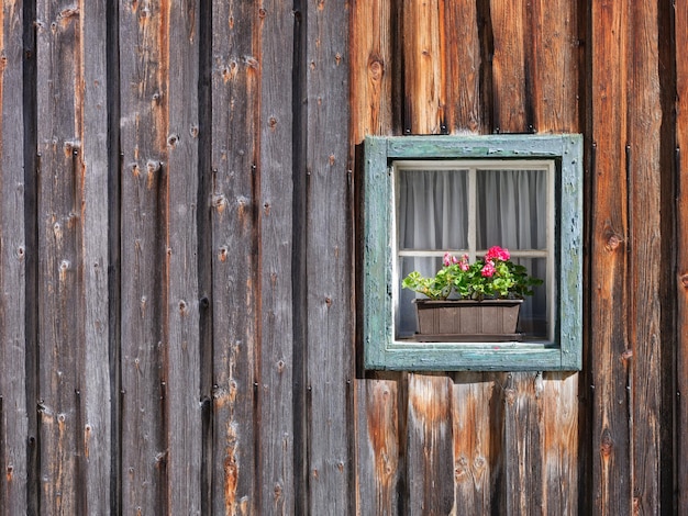 Window in the wall and potted flowers Vintage interior and exterior design of a house Wooden walls made of boards Large resolution photo for design