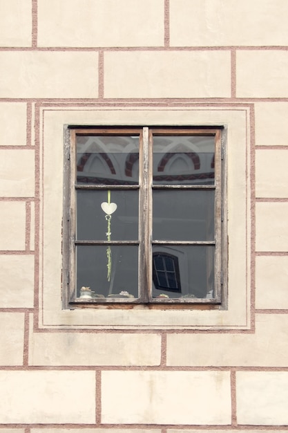 Window with old wooden frame decorated with hearts on a background of a white brick wall