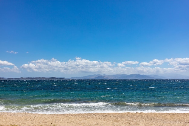 Windy sandy beach rough sea blue sky with clouds background