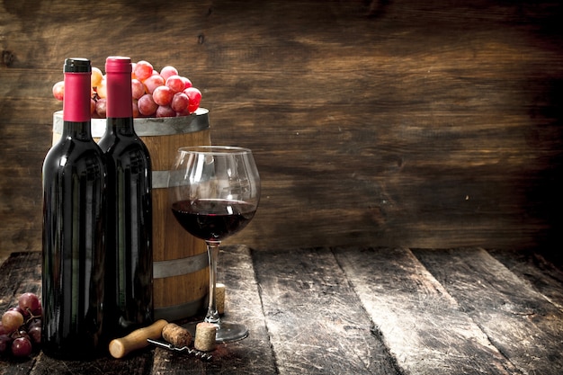 Wine background. A barrel with red wine and freshly grapes. On a wooden background.