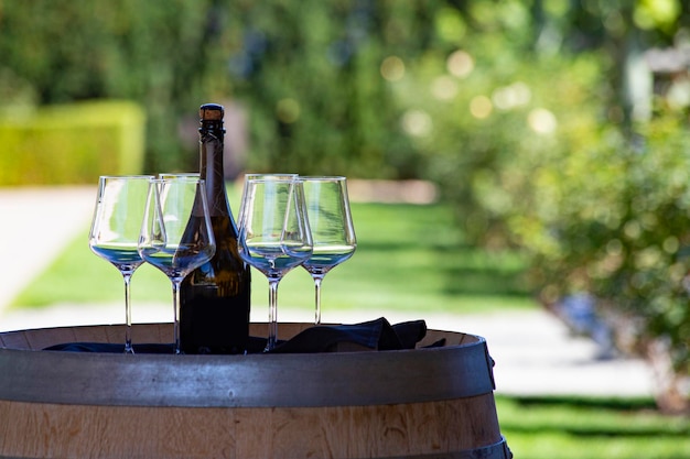 Wine bottle and four glasses on the wooden barrel. Welcome drink in winery shop.