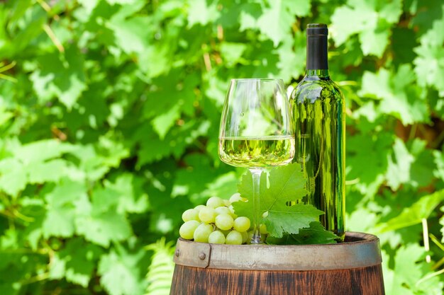 Wine bottle glass and grape on old wine barrel