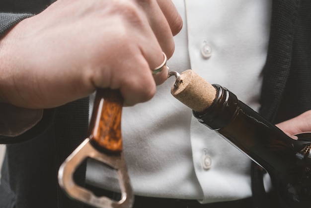 Wine bottle opening. Arms and corkscrew.