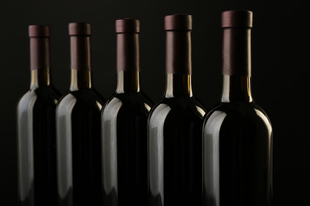 Wine bottles in a row on black background close up