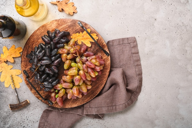 Wine bottles with grapes and wineglasses on old gray concrete table background with copy space. Red wine with a vine branch. Wine composition on rustic background. Mock up.